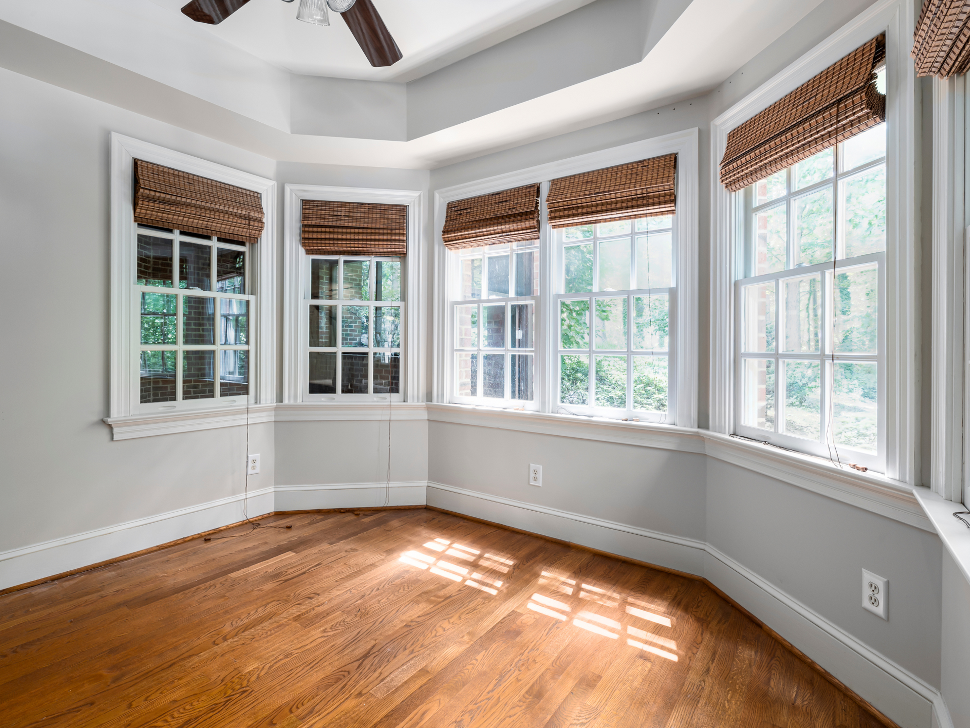 An gray painted room with windows and a ceiling fan.