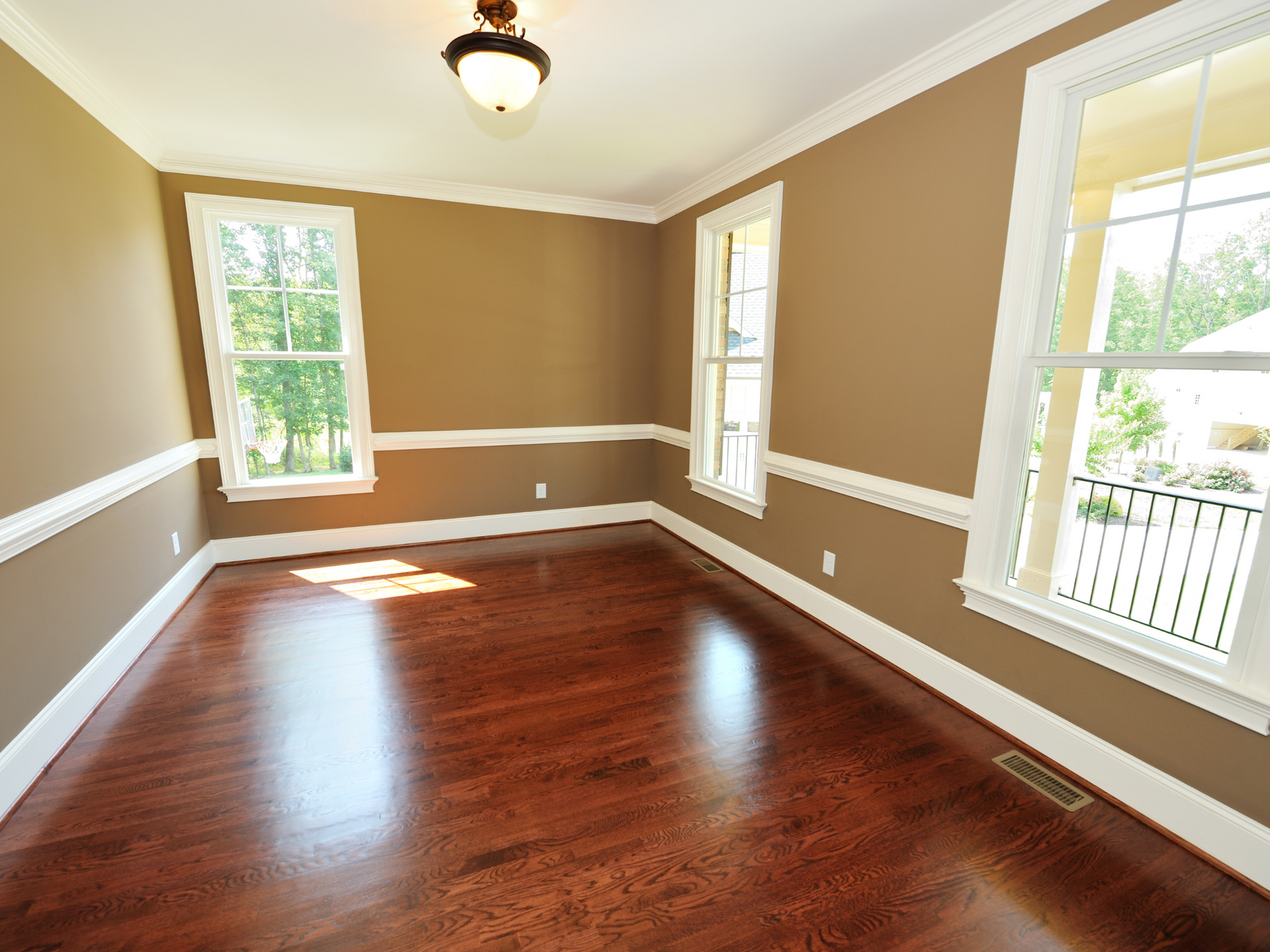 An empty room with hardwood floors and caramel colored walls