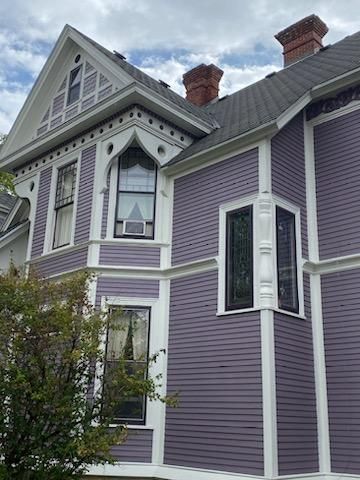 A large purple and white house with a chimney on the roof.