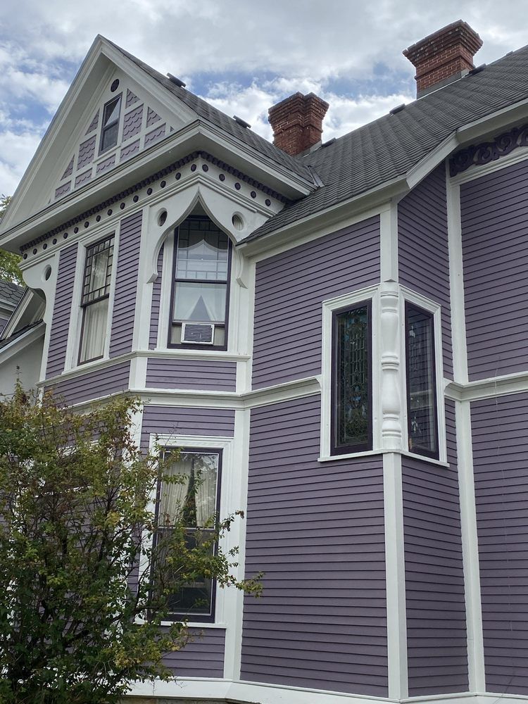 An old purple and white house with a chimney on the roof.