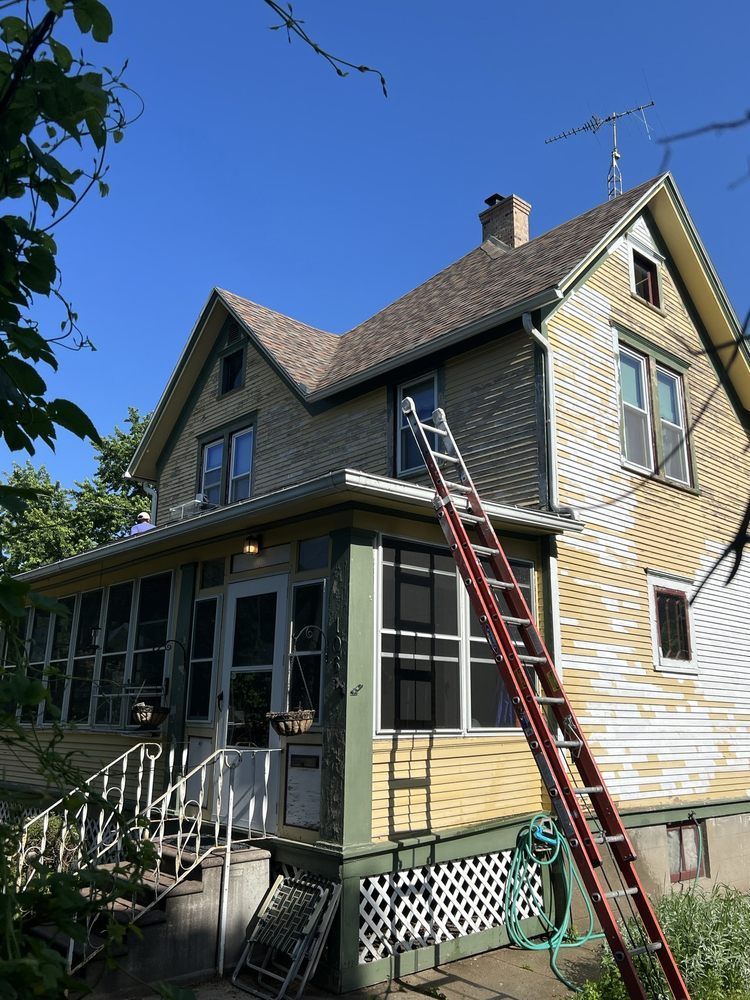 A ladder is leaning against the side of a house being prepared for paint