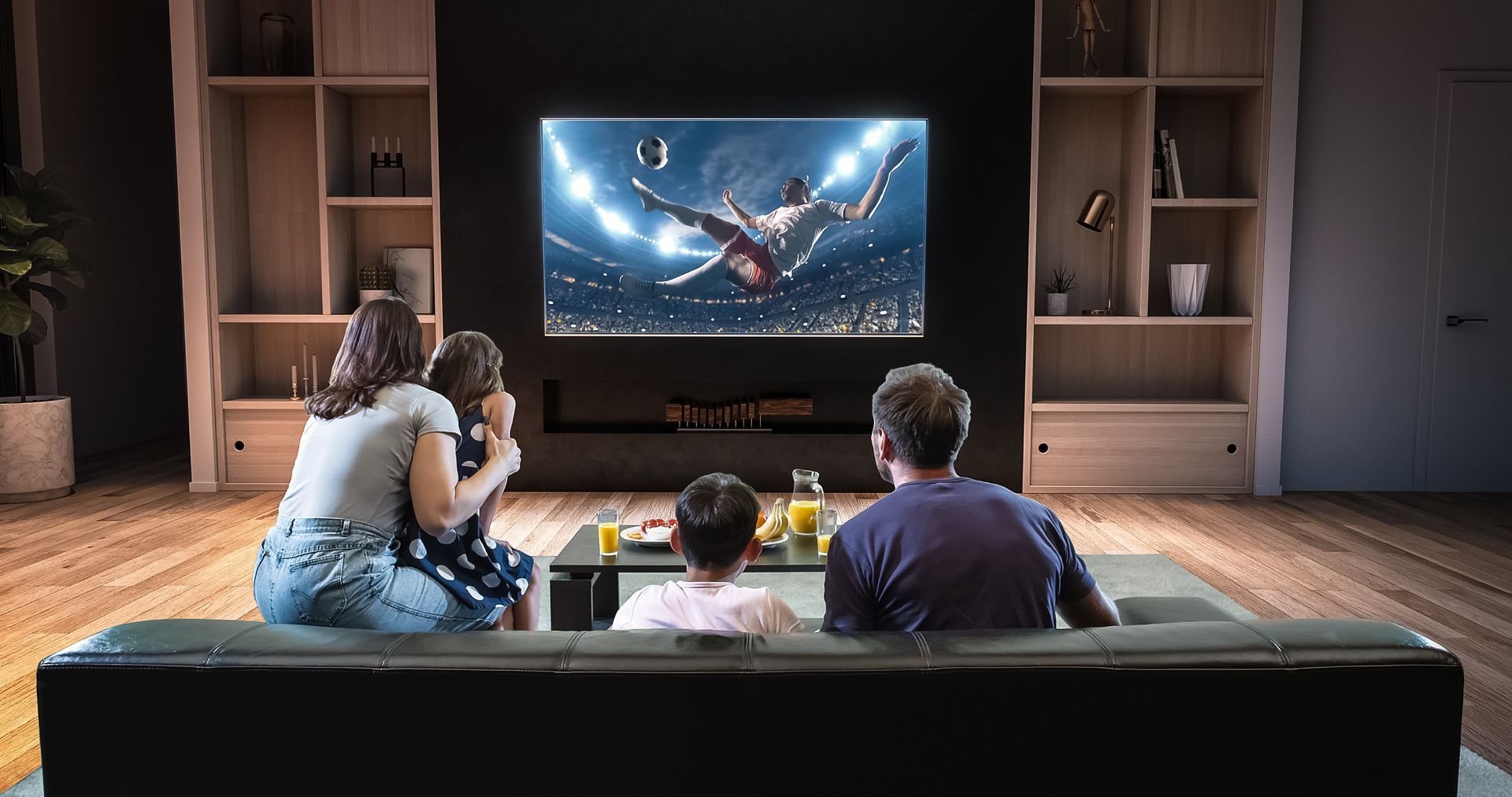 Family watching soccer on a large TV in a modern living room, with anticipation.