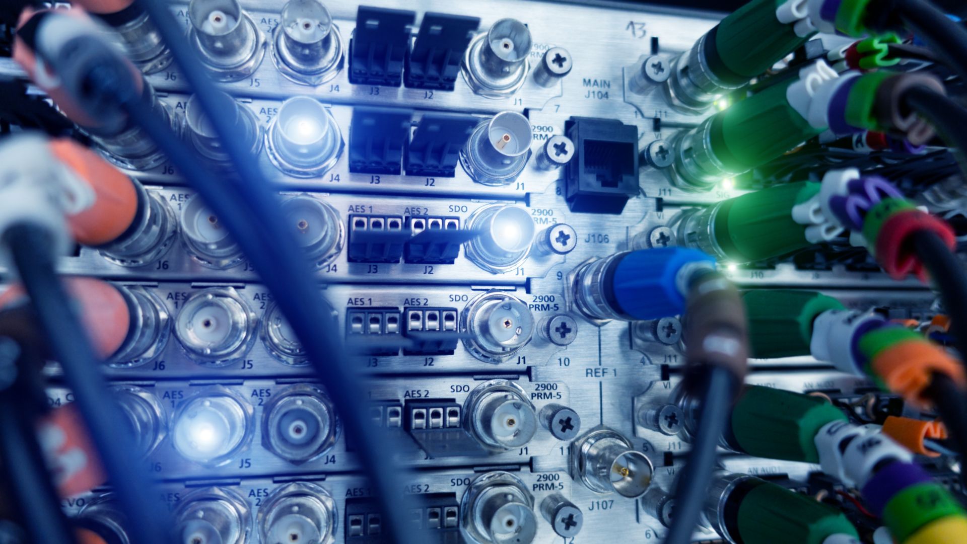Close-up of a server panel with various connected cables in multiple colors and glowing lights.
