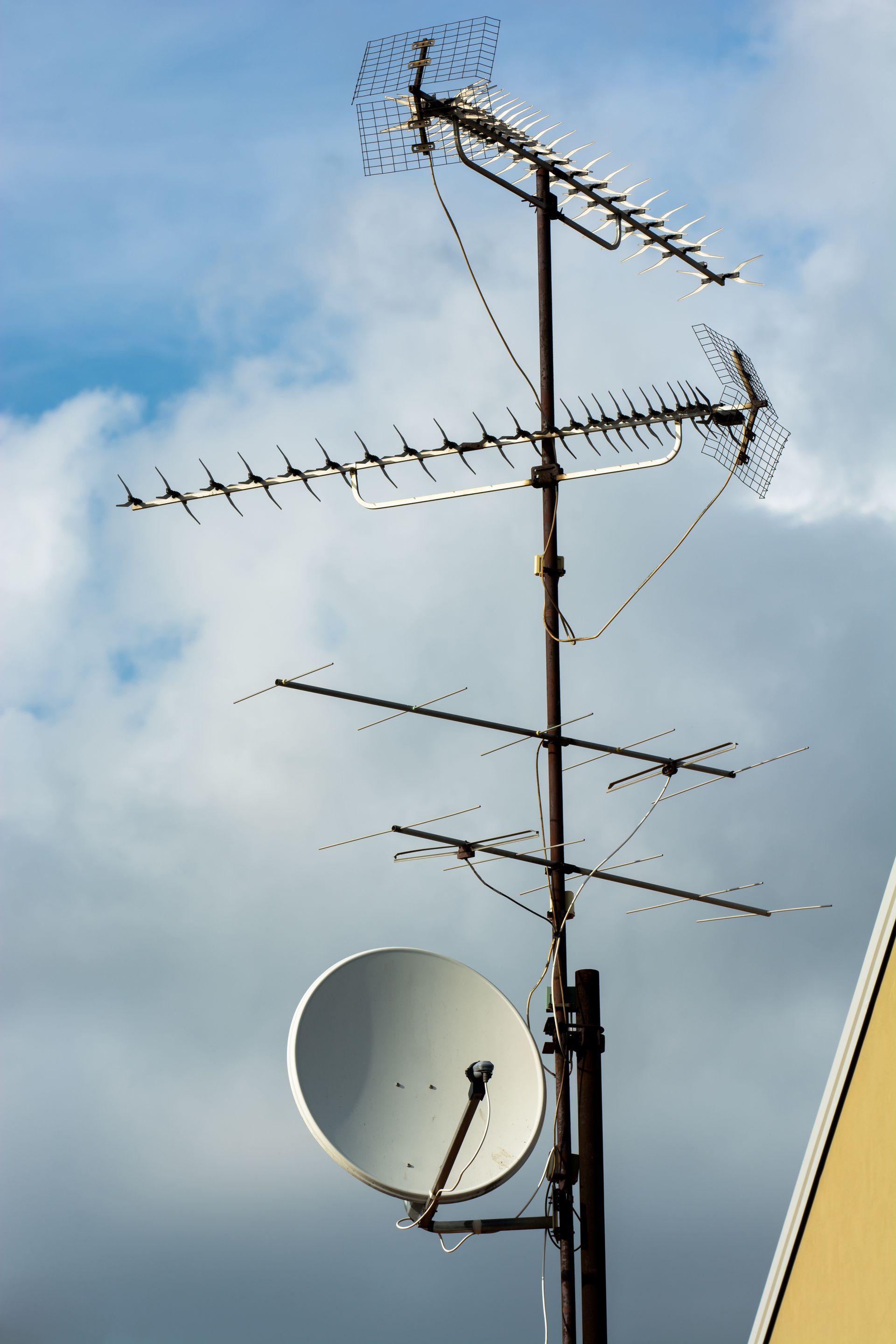 Person in a hard hat installing a satellite dish on a roof.