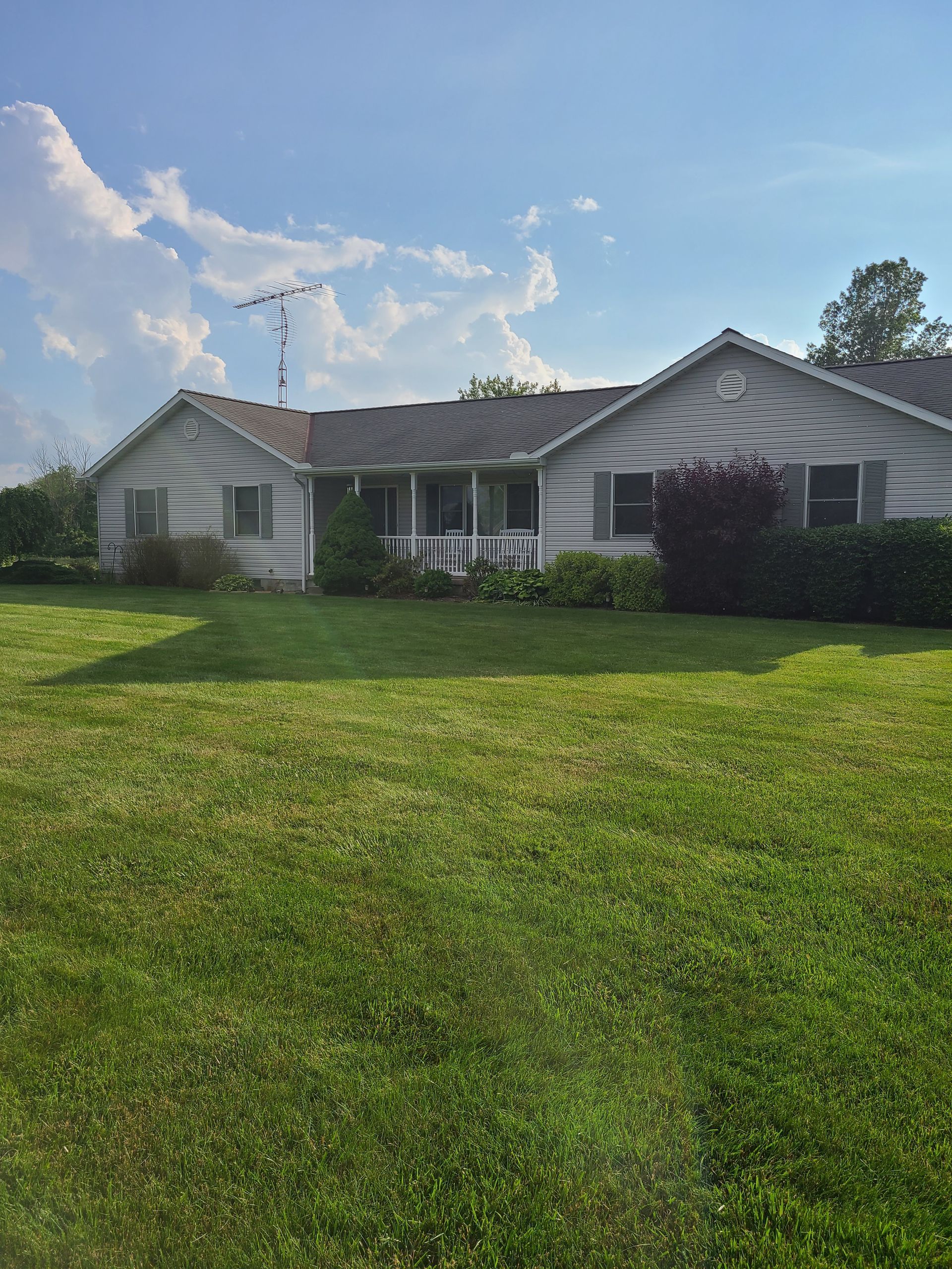 Person connecting white coaxial cables to a metal component, with a blue sky background.
