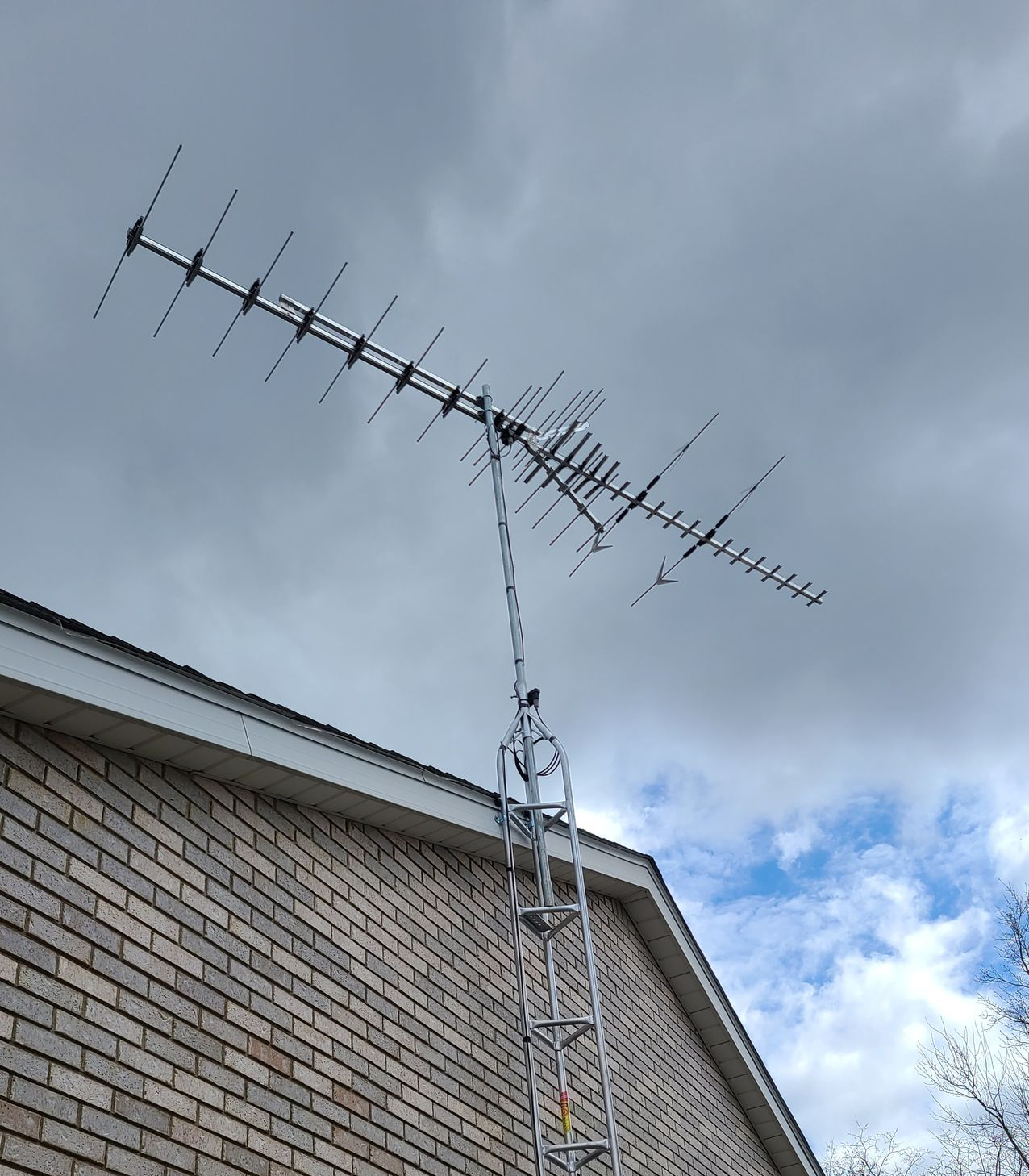 Man in red cap installs a satellite dish on a building. Blue sky.