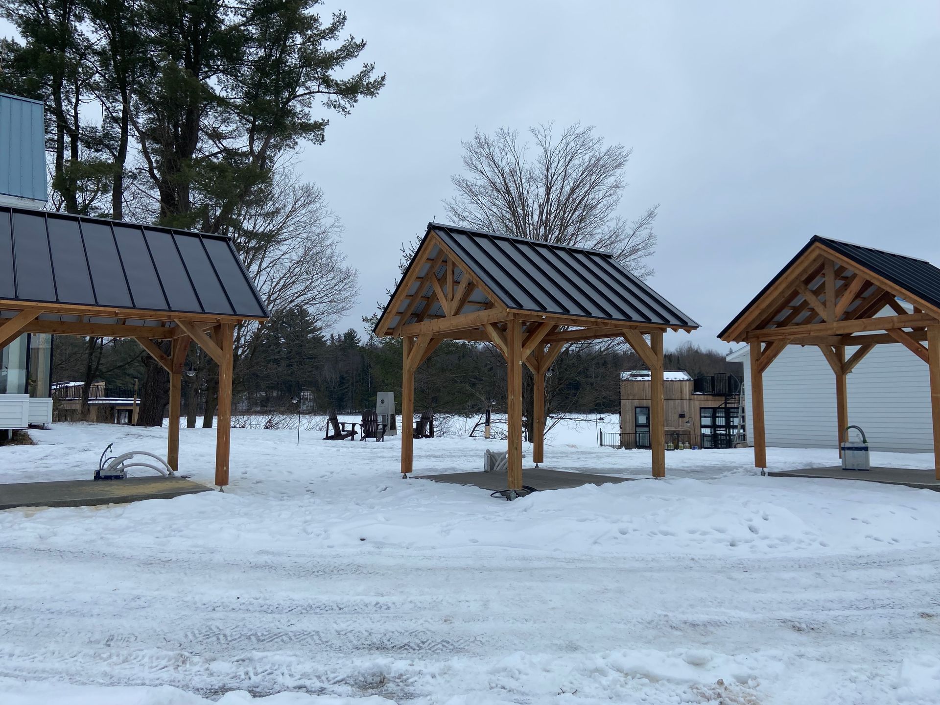 Une rangée de structures en bois dans la neige avec un toit en métal
