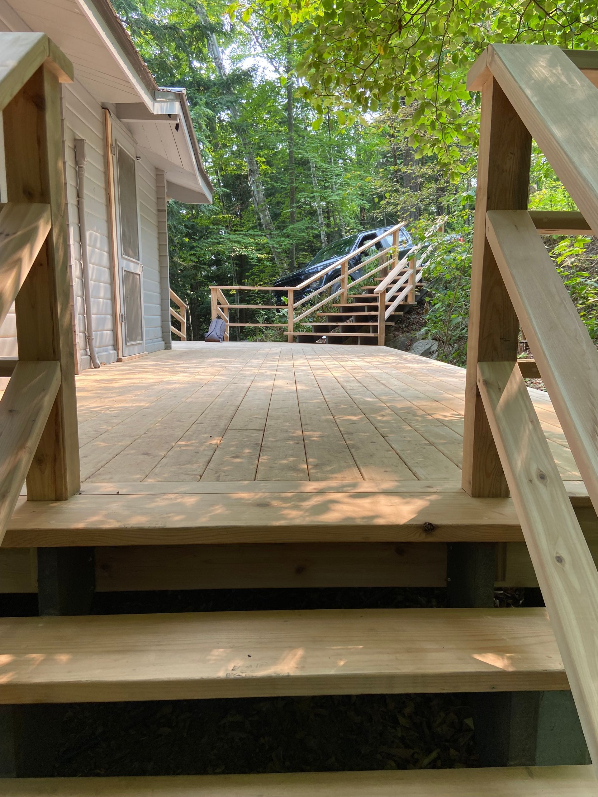 Une terrasse en bois avec des escaliers qui y mènent et une maison en arrière-plan.