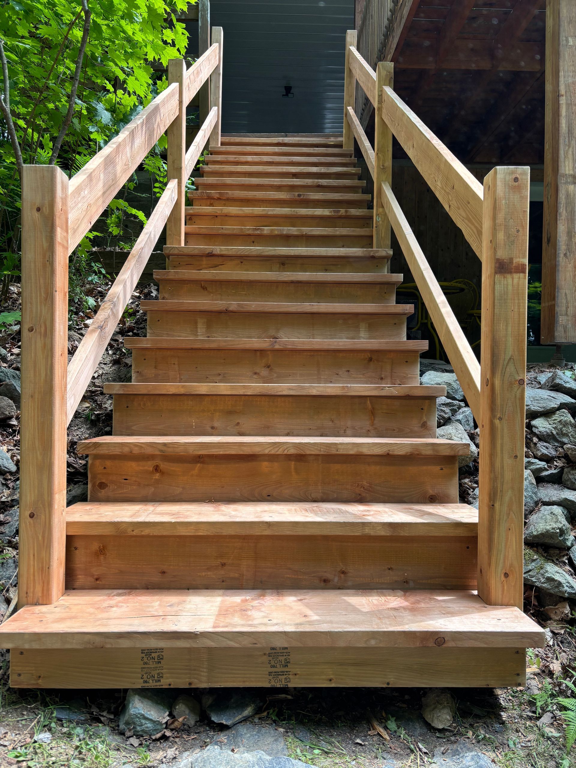 Un ensemble d'escaliers en bois avec une rampe en bois menant à une maison.