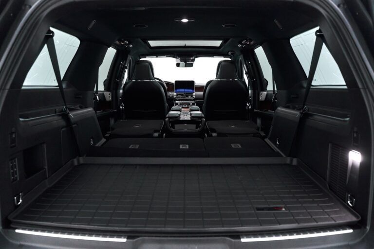 Interior view of a black SUV cargo area with second-row seats folded flat, a cargo liner, and ambient lighting.