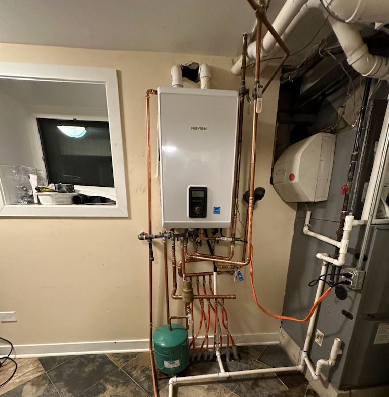 White wall-mounted boiler with copper pipes in a basement.