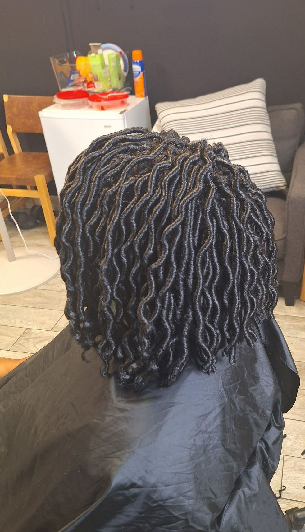 A woman is sitting in a chair with blue curlers in her hair.