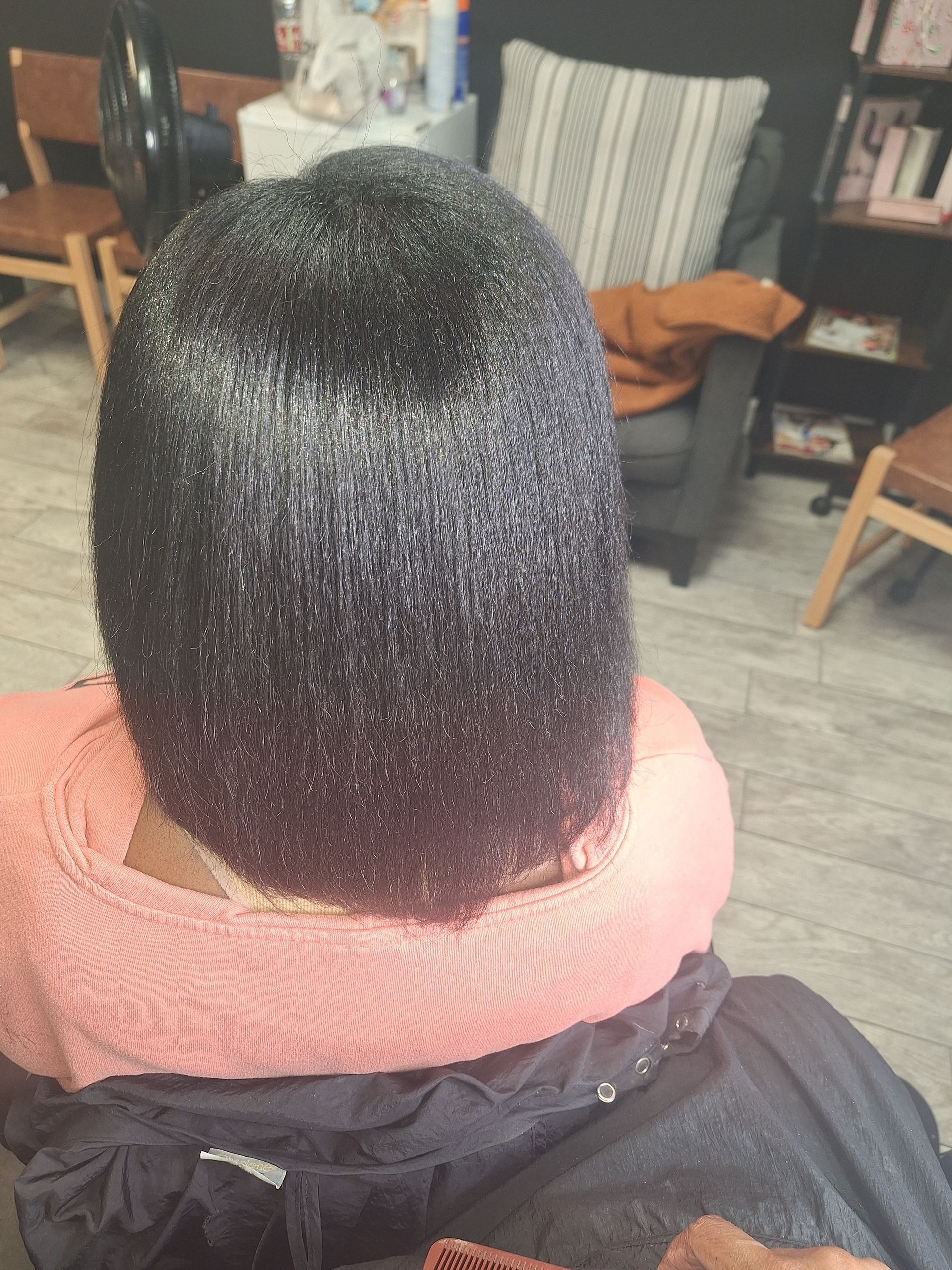 A woman is sitting in a chair with her hair in a bun.