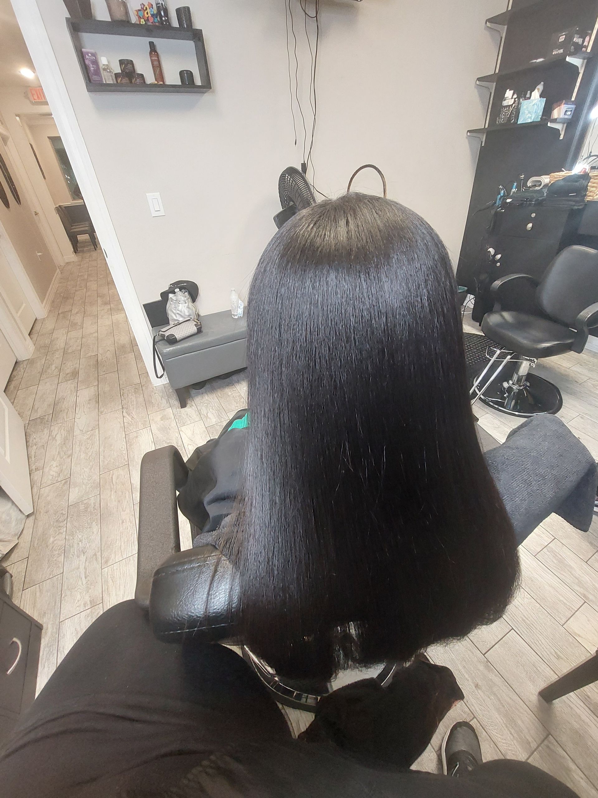A woman is sitting in a chair with her hair in a salon.