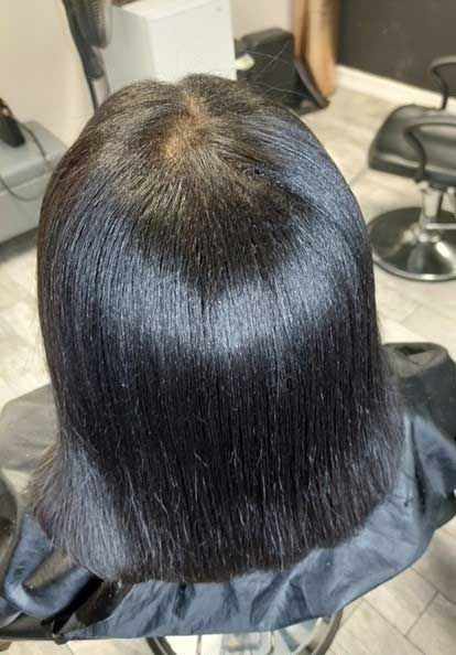 A woman is sitting in a chair with her hair cut in a salon.