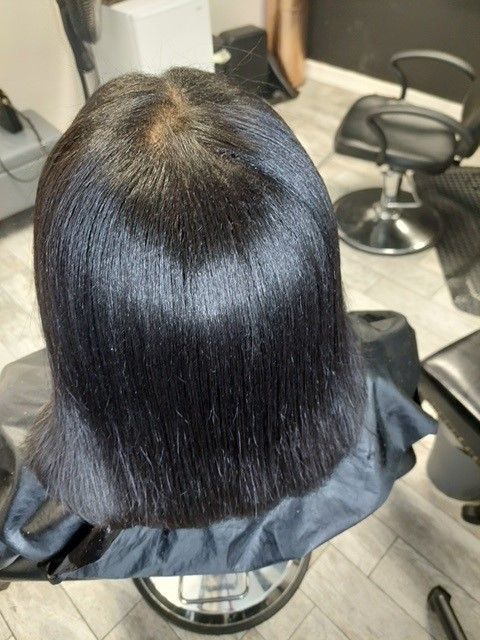A woman is sitting in a chair with her hair cut in a salon.