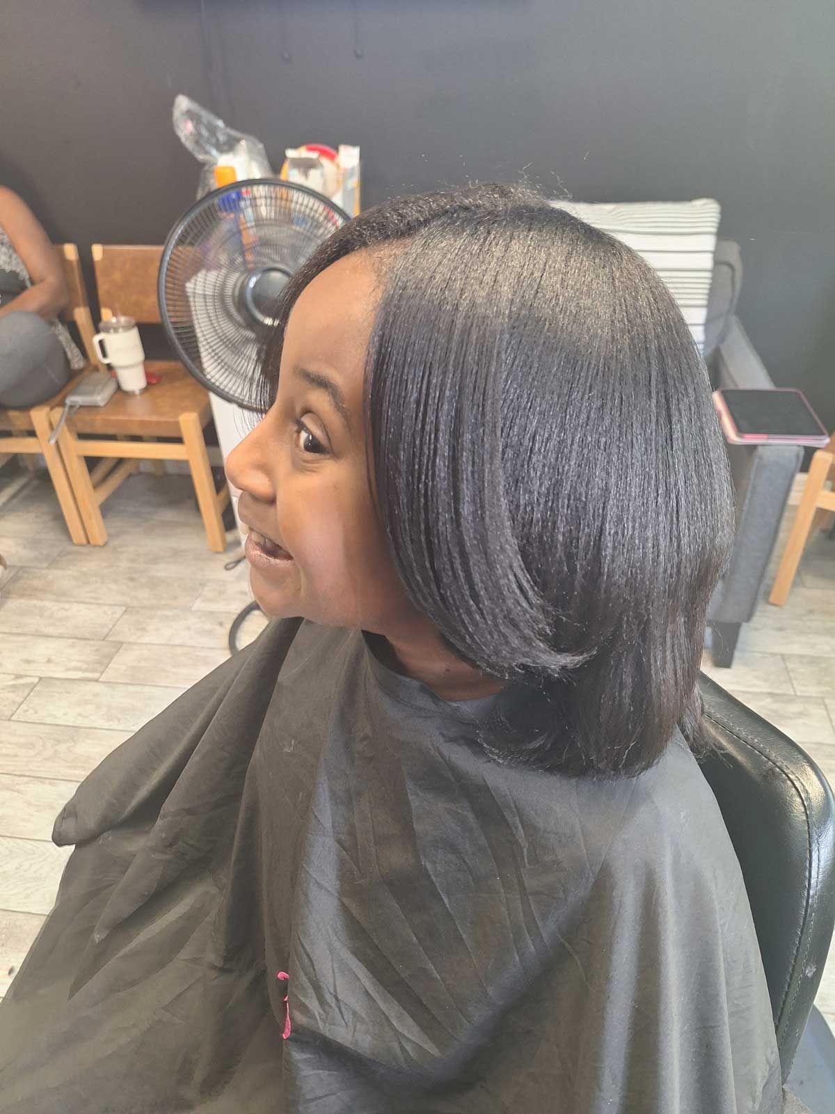 A little girl is getting her hair cut at a salon.