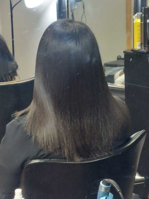 A woman with long hair is sitting in a chair in front of a mirror.