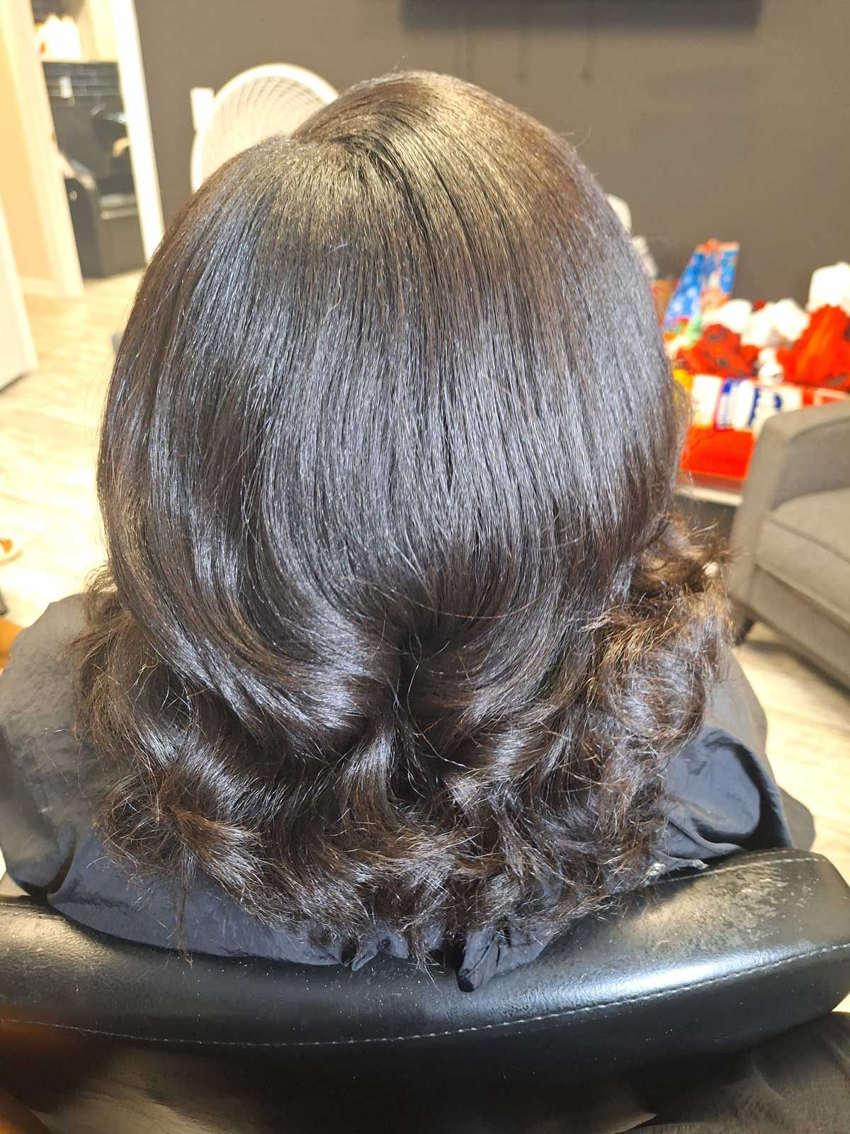 A woman is sitting in a chair with her hair in a bun.