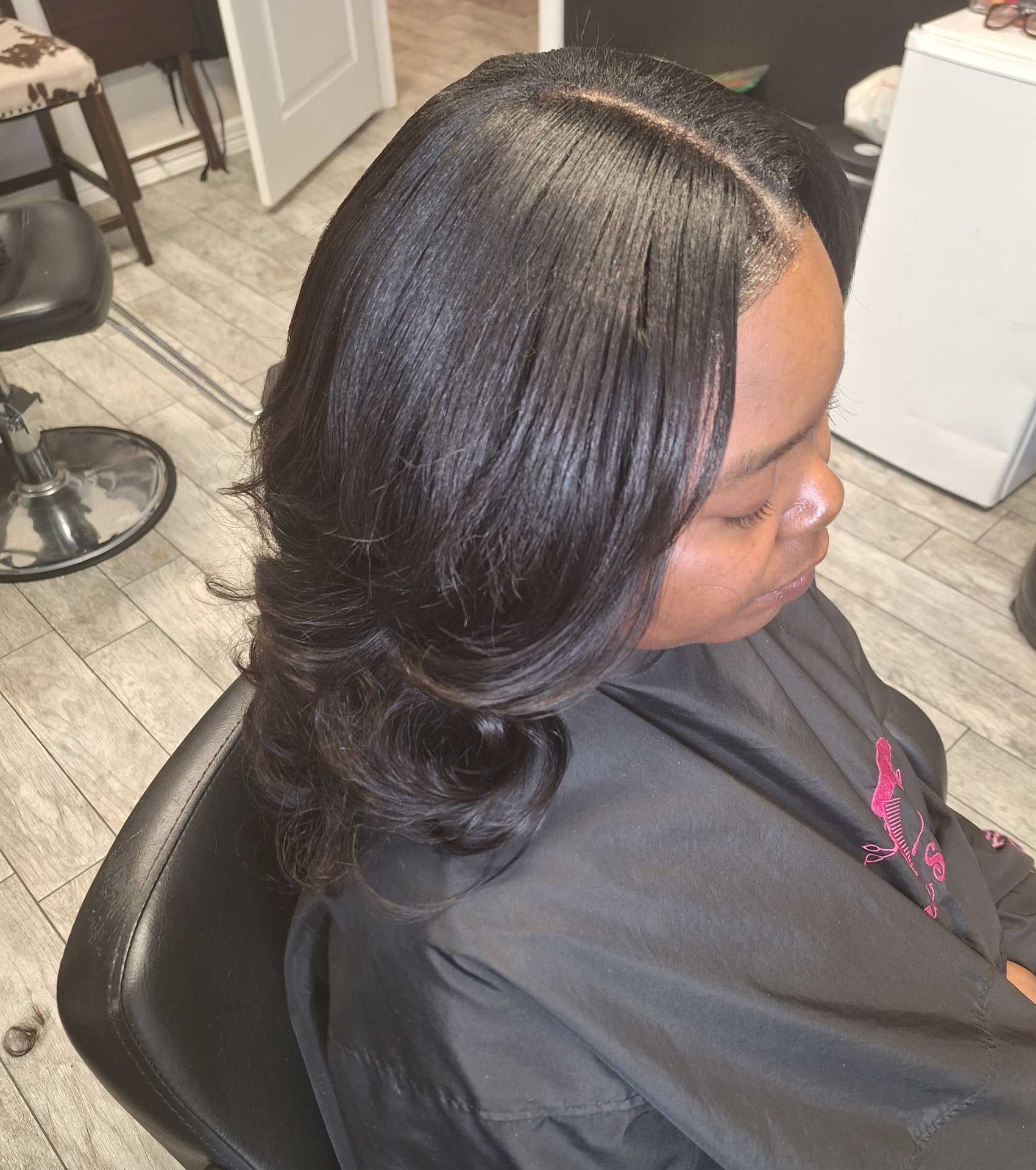 A woman is sitting in a chair with her hair in a salon.