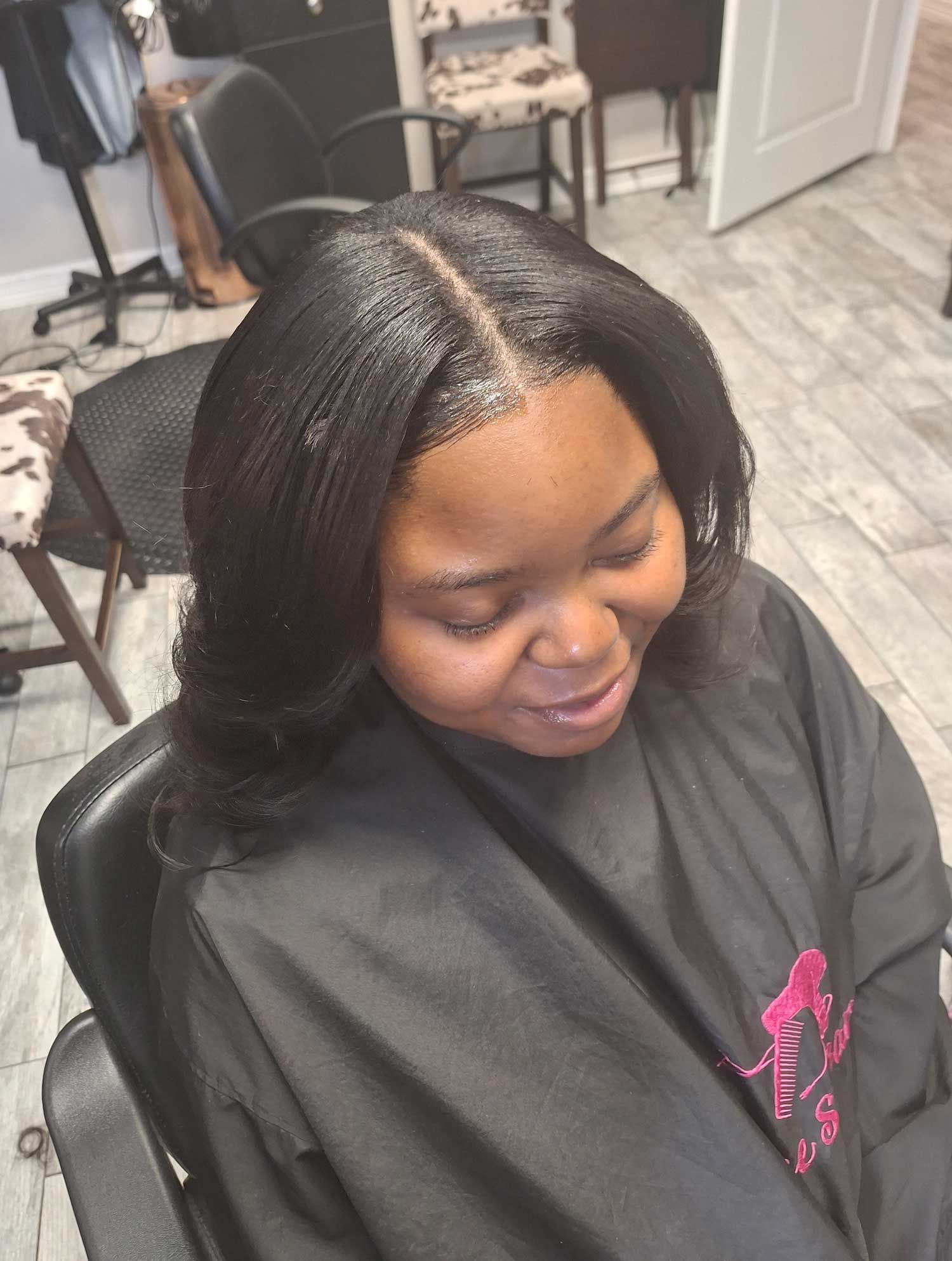 A woman is sitting in a chair with her hair in a salon.