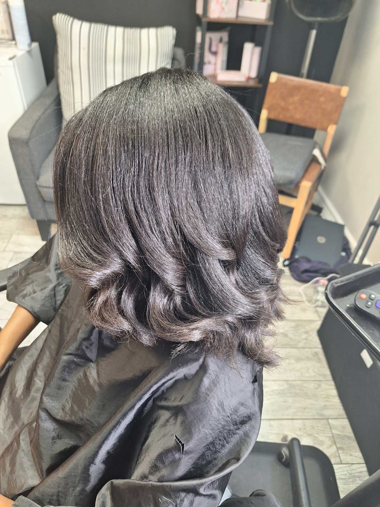 A woman is sitting in a chair with her hair in a salon.