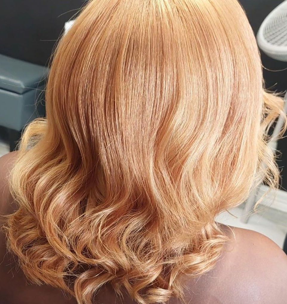 A woman with orange hair is sitting in a chair in a salon.
