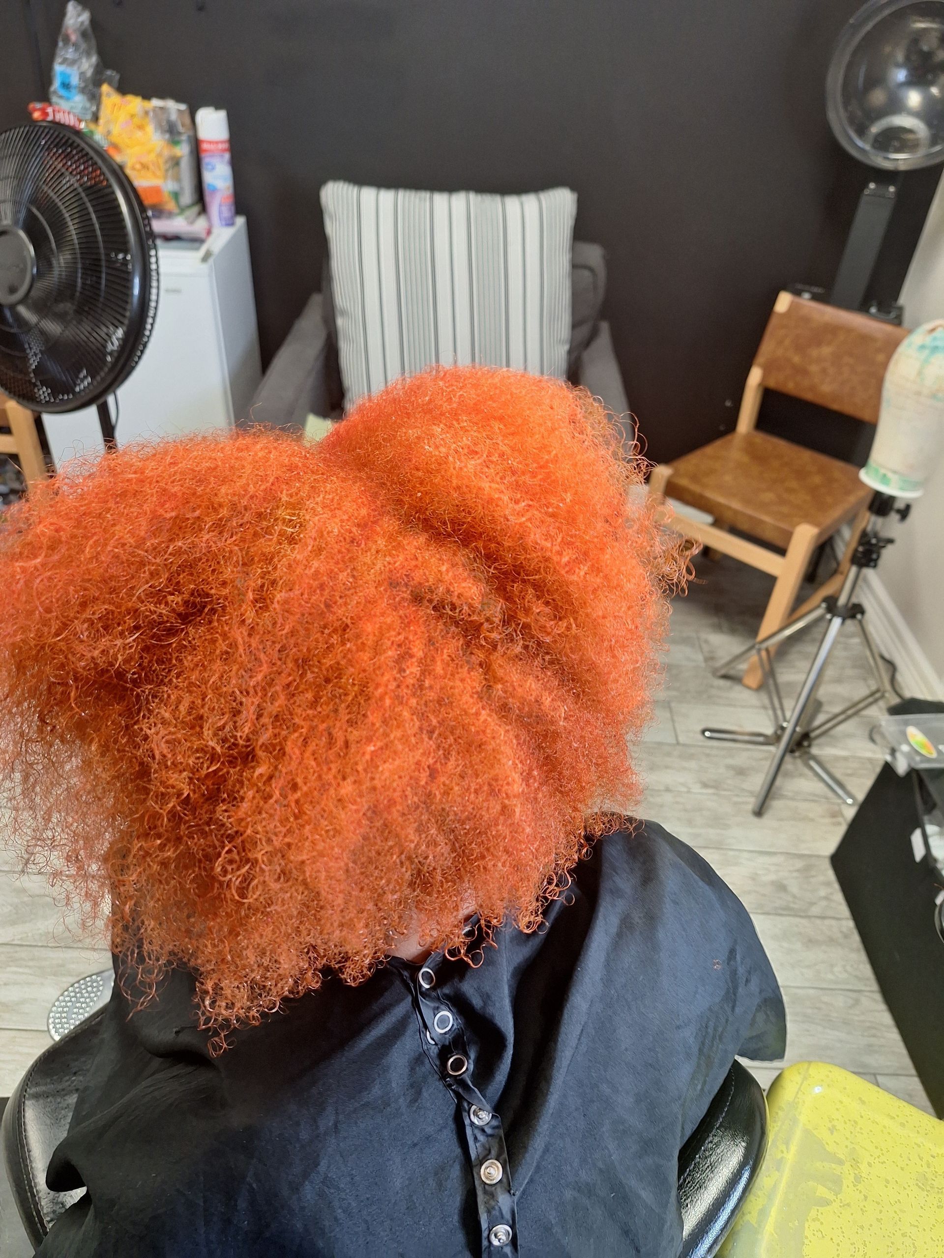 A woman with red hair is sitting in a chair in a salon.