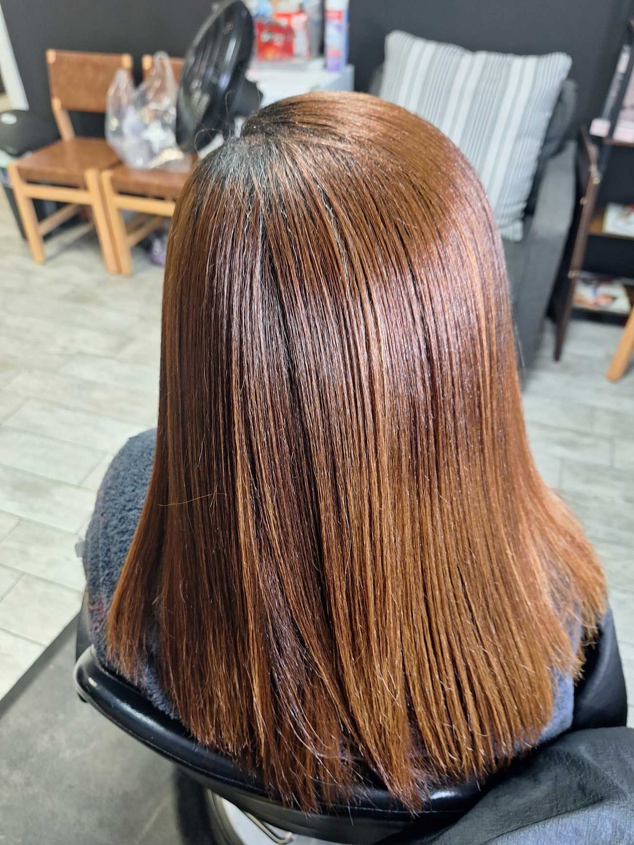 A woman with long brown hair is sitting in a chair in a salon.