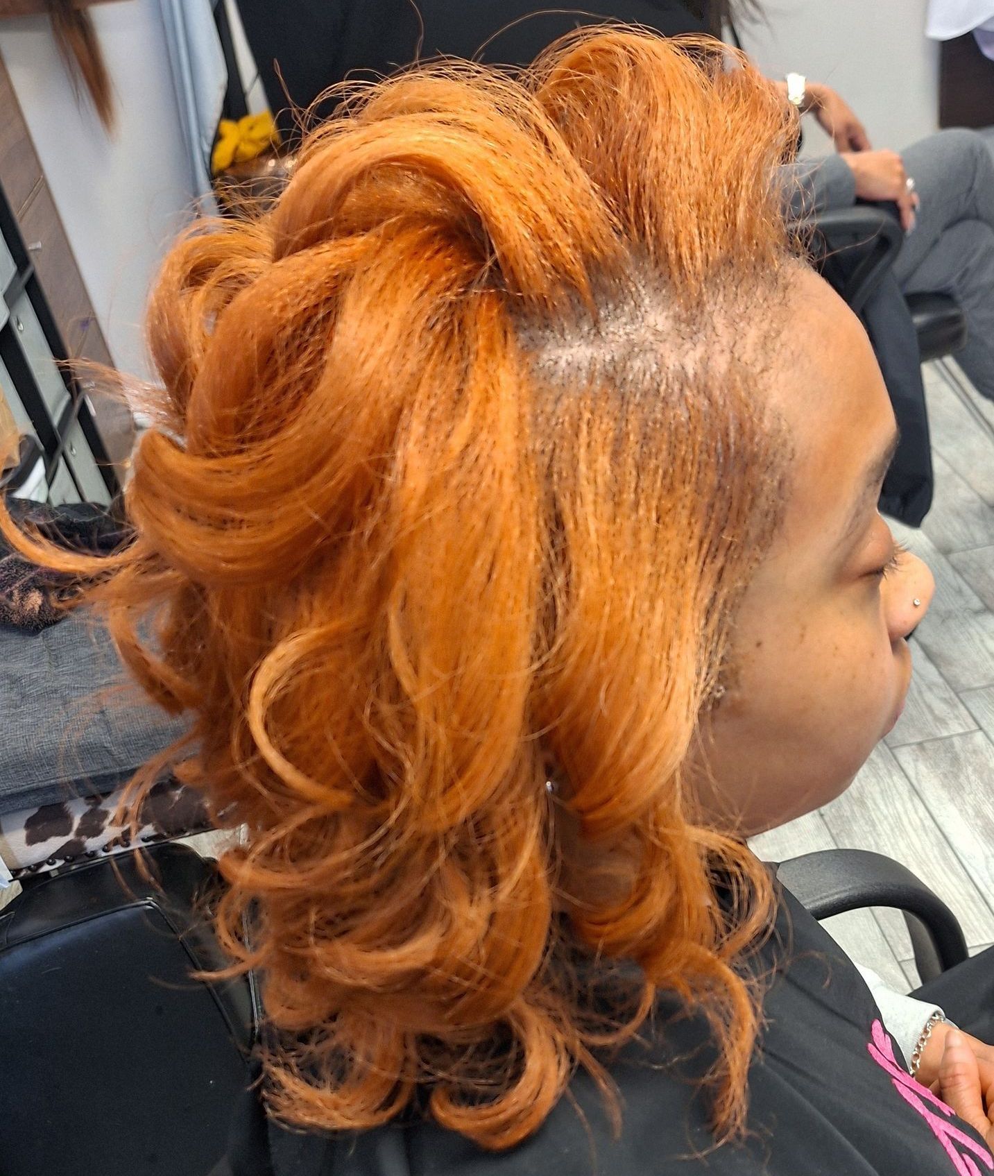 A woman with long brown hair is sitting in a chair in a salon.