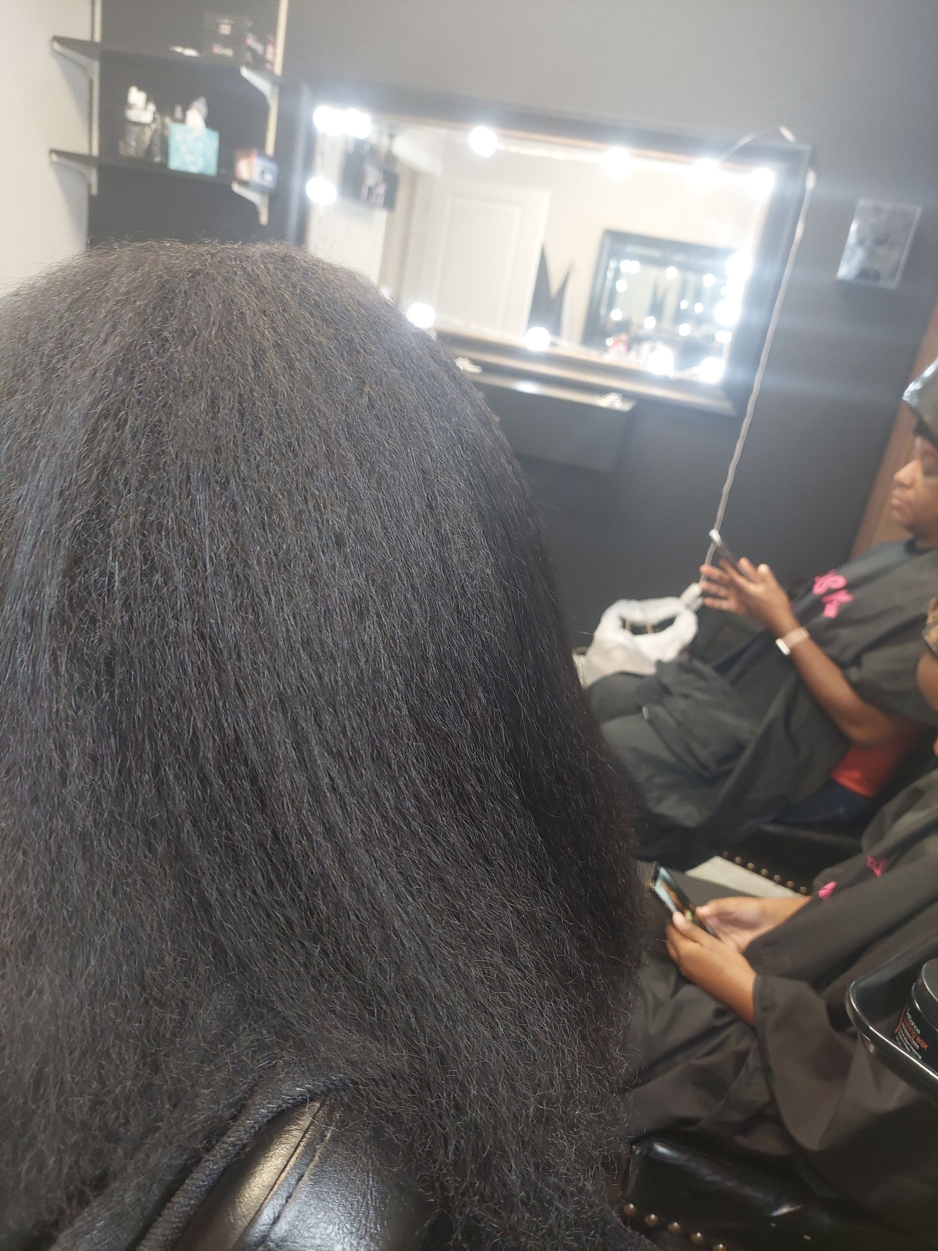 A woman is taking a picture of her hair in front of a mirror