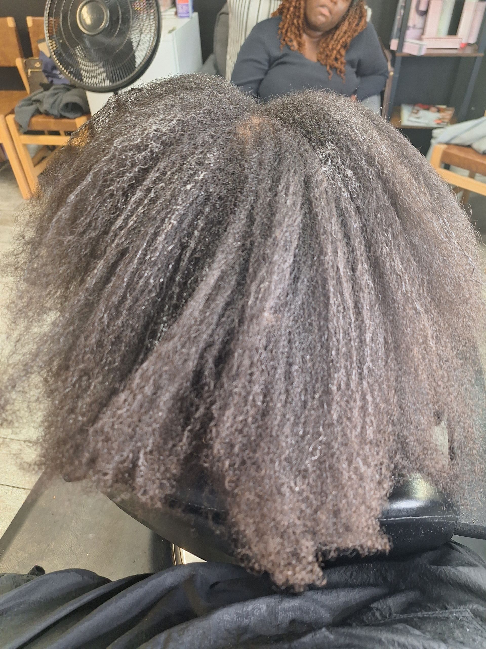 A woman is sitting in a chair with her hair in a bun.