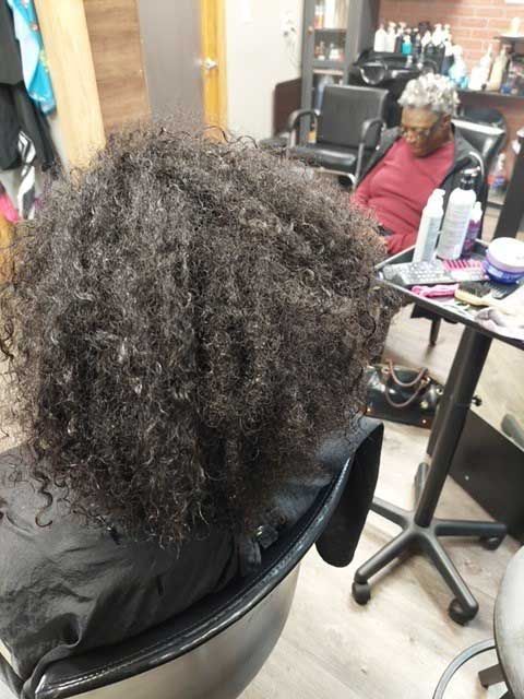 A woman with curly hair is sitting in a chair in a salon.