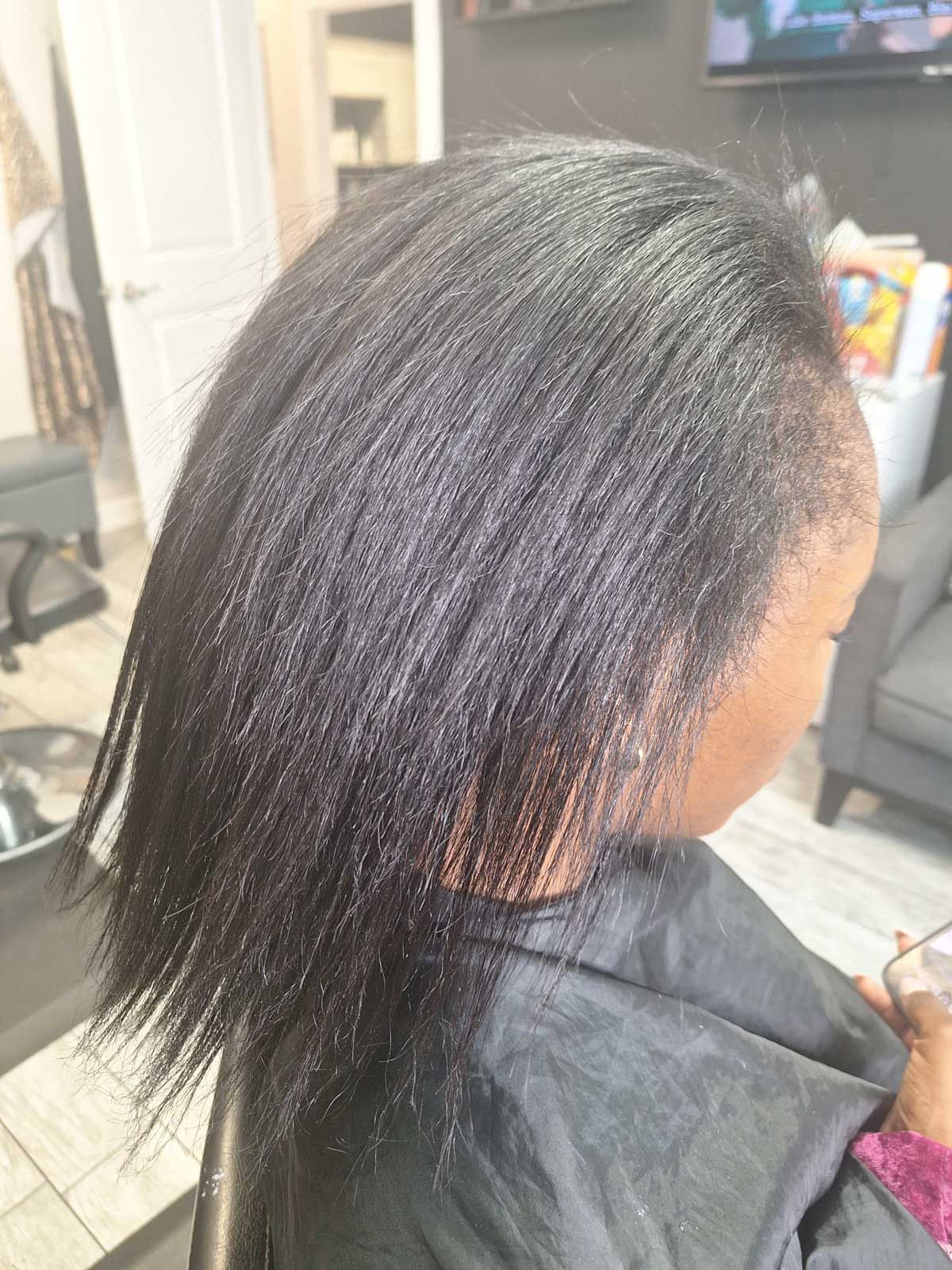 A woman is sitting in a chair with her hair in a salon.