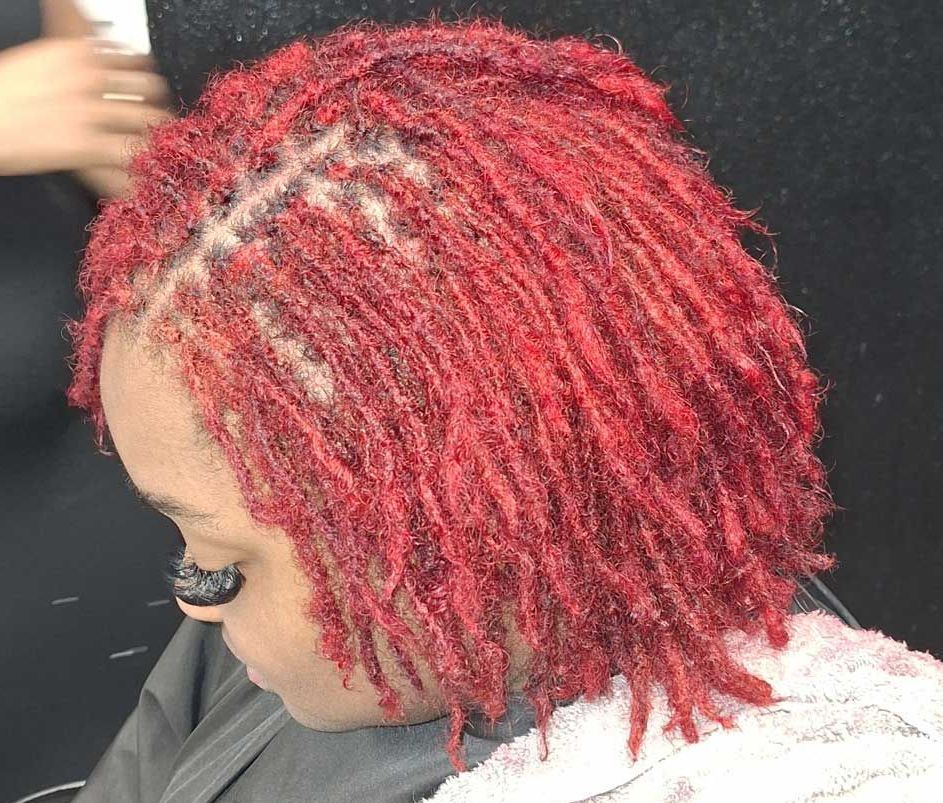 A woman with red hair is sitting in a chair with a towel around her neck.