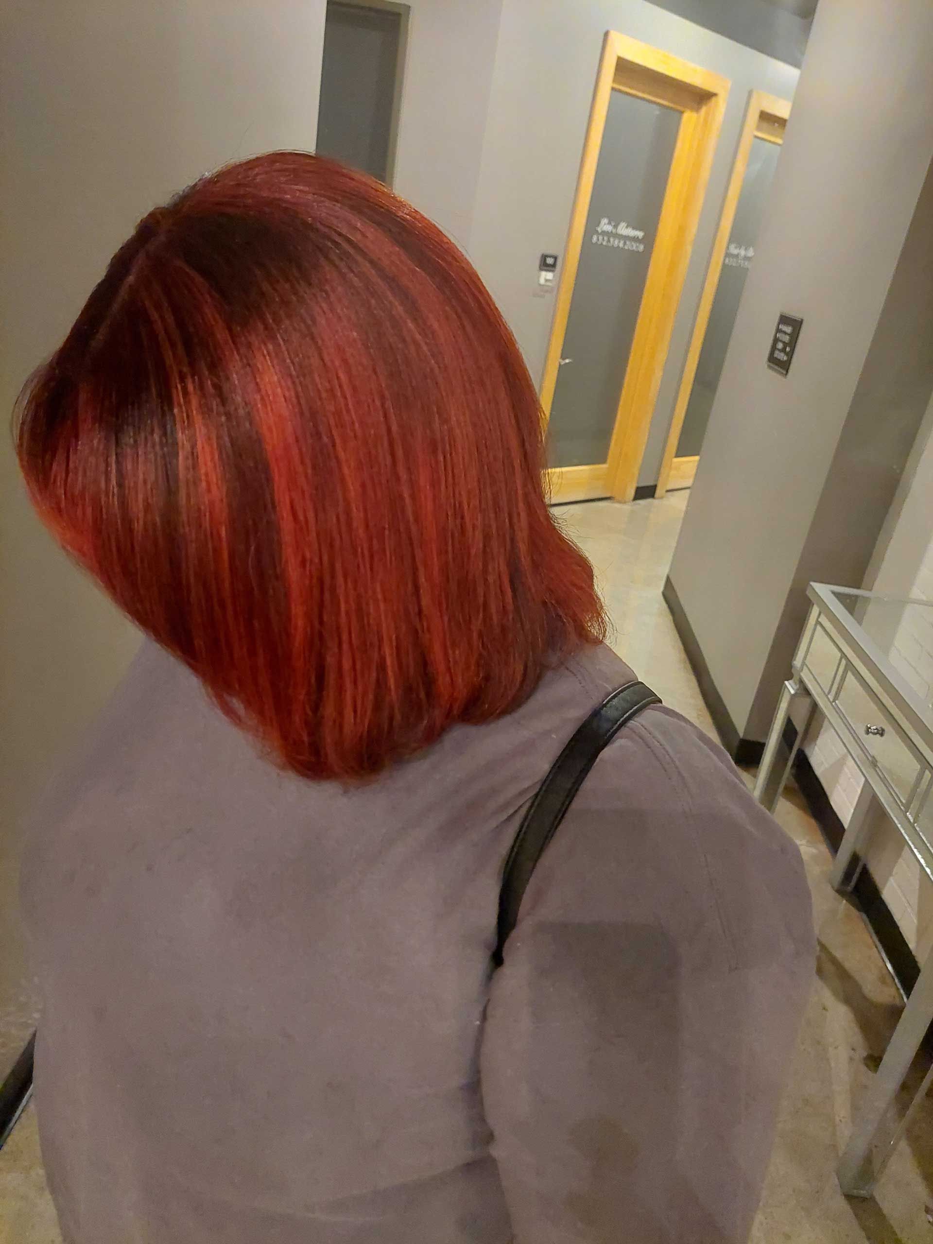 A woman with red hair is standing in a hallway.
