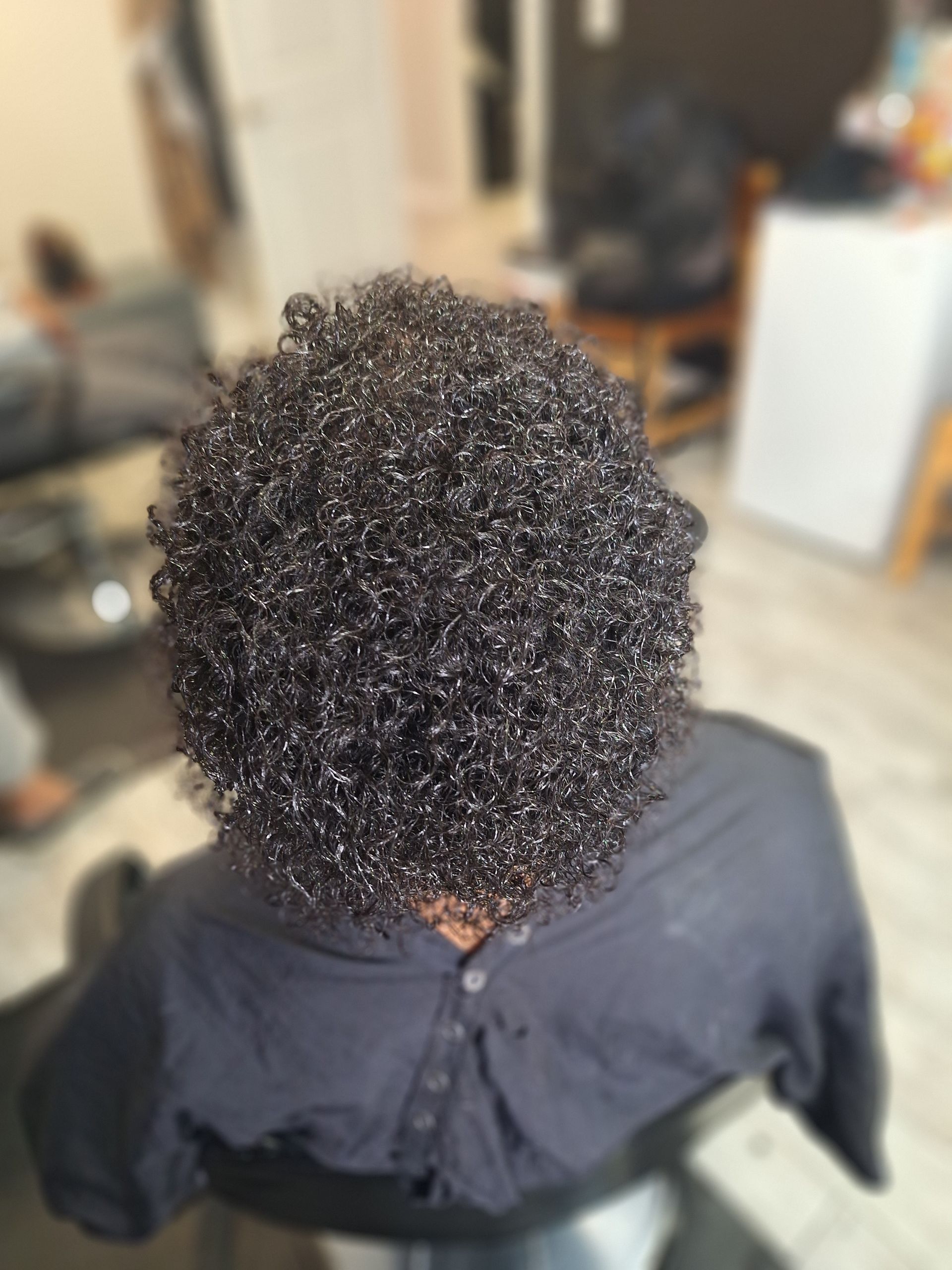 A woman with curly hair is sitting in a chair in a salon.