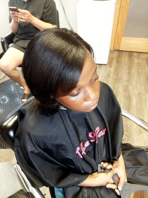 A woman is sitting in a chair wearing a black cape that says the star