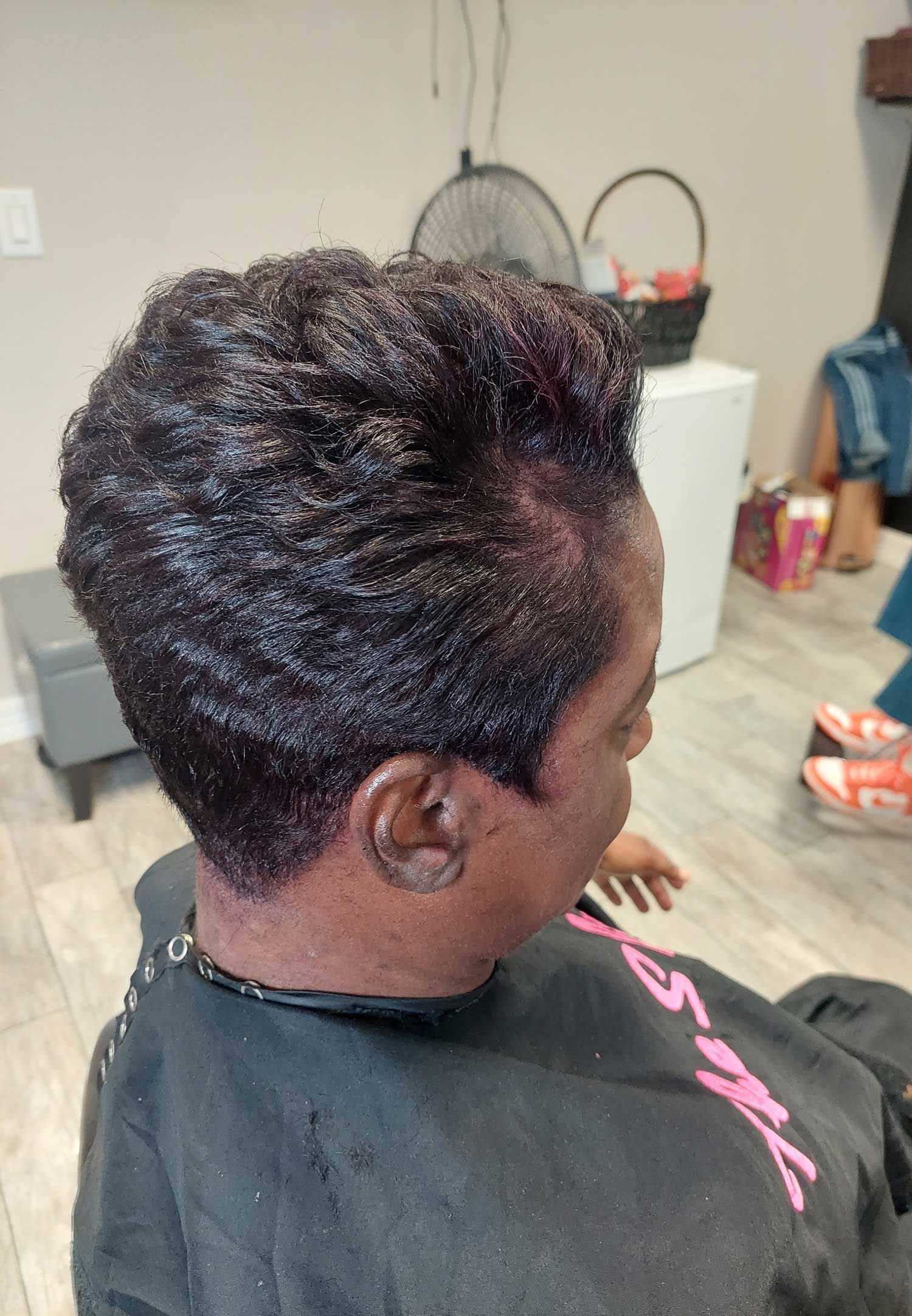 A woman is getting her hair cut at a barber shop.