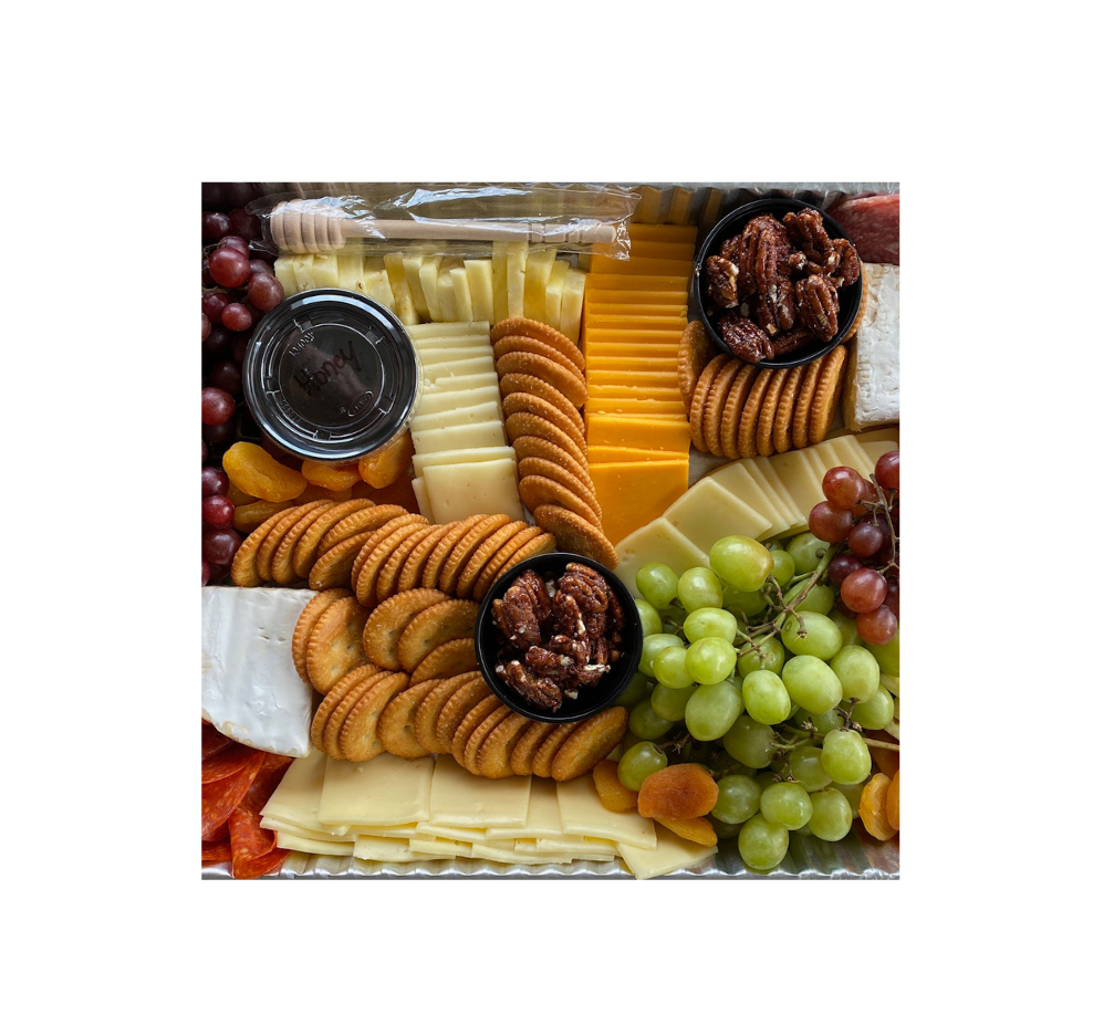 A tray filled with cheese , crackers , grapes and meat