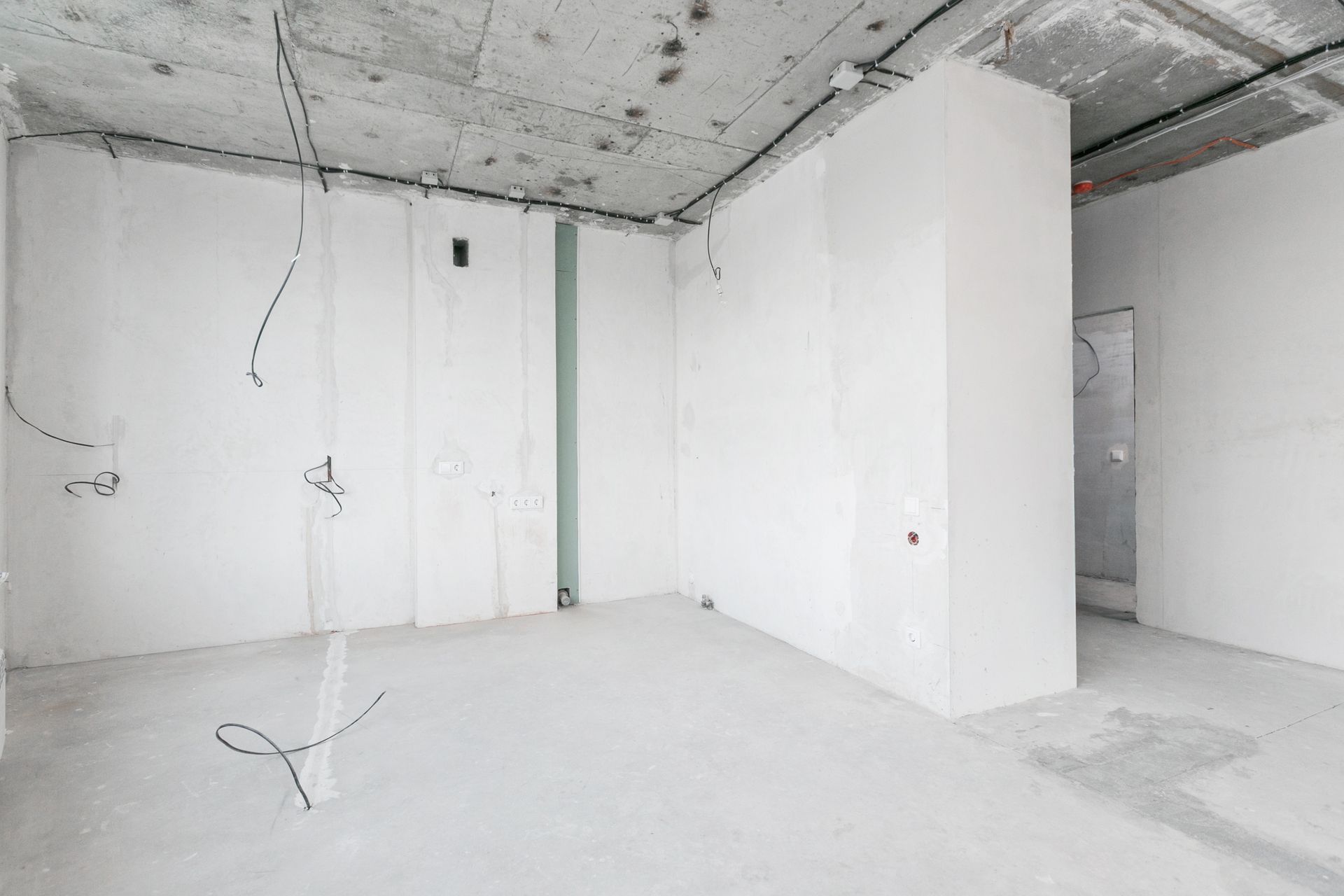 An empty room with white walls and a concrete floor.