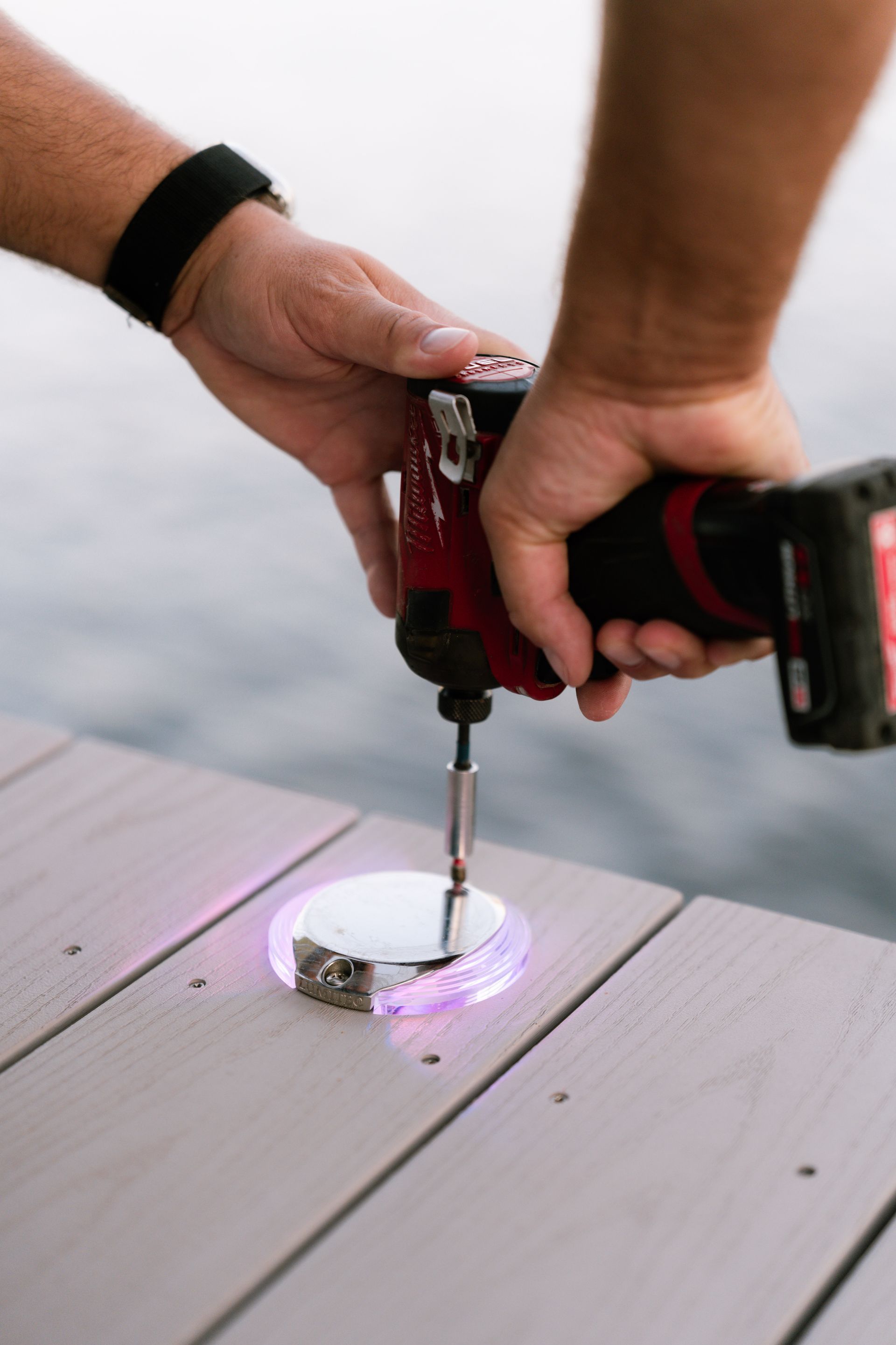 A person is using a drill on a wooden deck