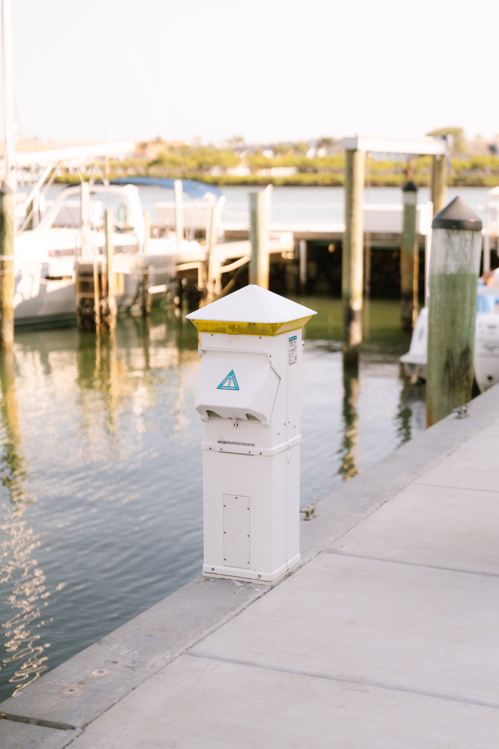 A white pole with a yellow top is next to a body of water.