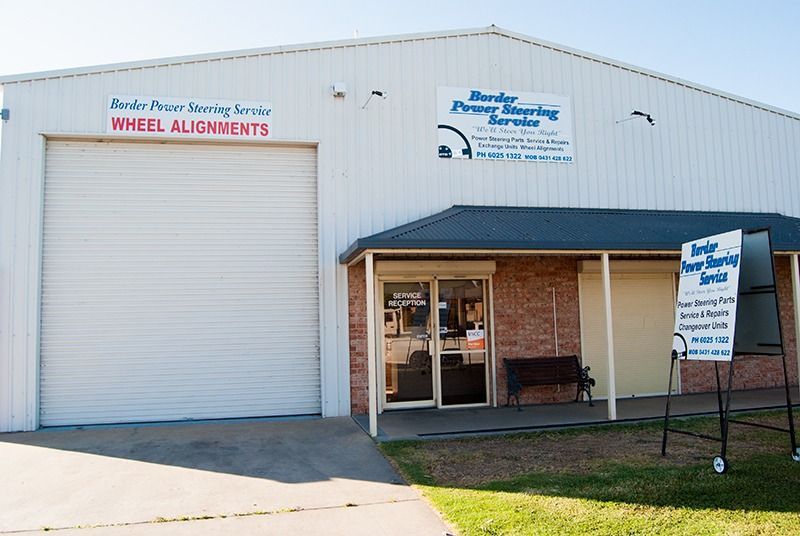 A White Building With a Red Sign That Says Wheel Alignments — Border Power Steering Service In Lavington, NSW
