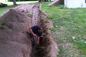 A man digging a trench for plumbing repair services in Newport, RI