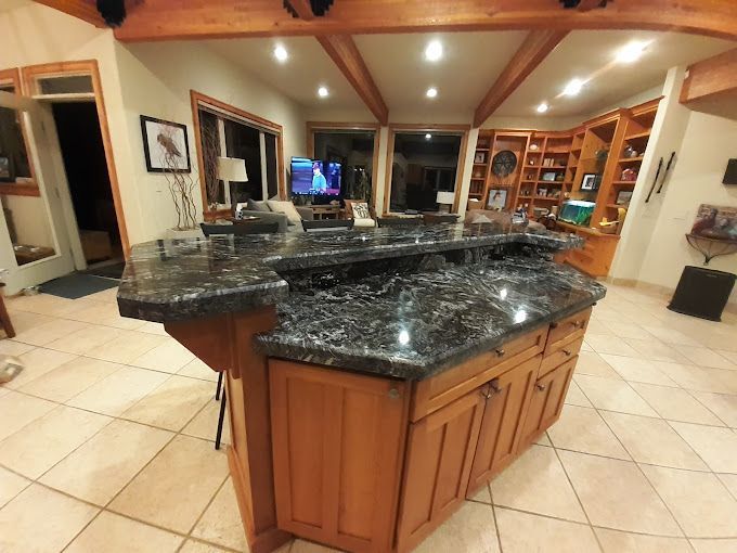 A kitchen with marble counter tops and wooden cabinets