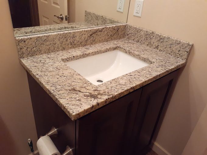 A bathroom sink with a granite counter top and a mirror