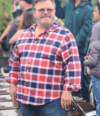 Man in plaid shirt standing outside.