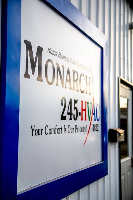 Monarch HVAC sign on building exterior, with blue frame, and text including phone number.