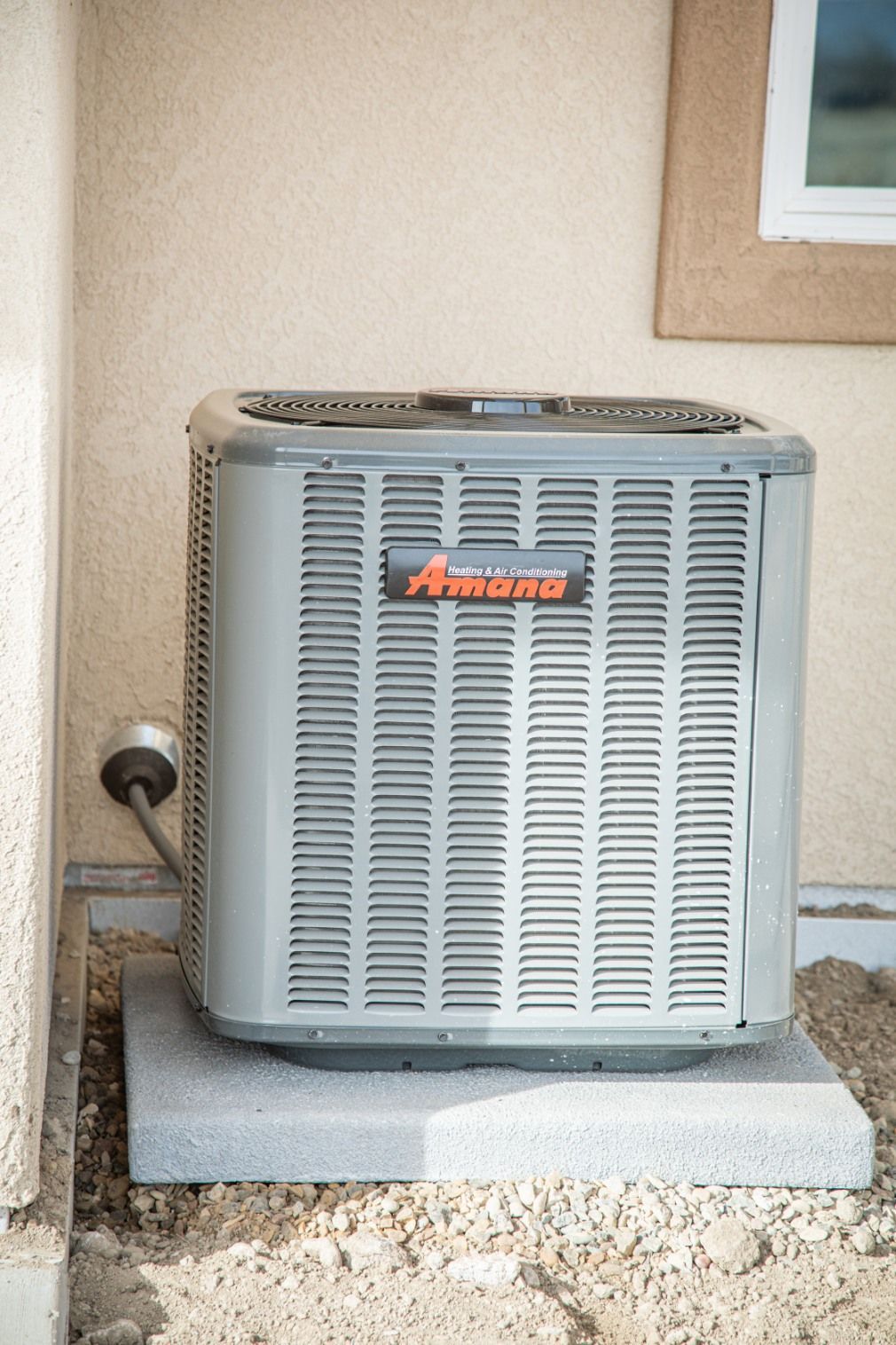 Woman in straw hat smiles, holding wine glass near a lake.